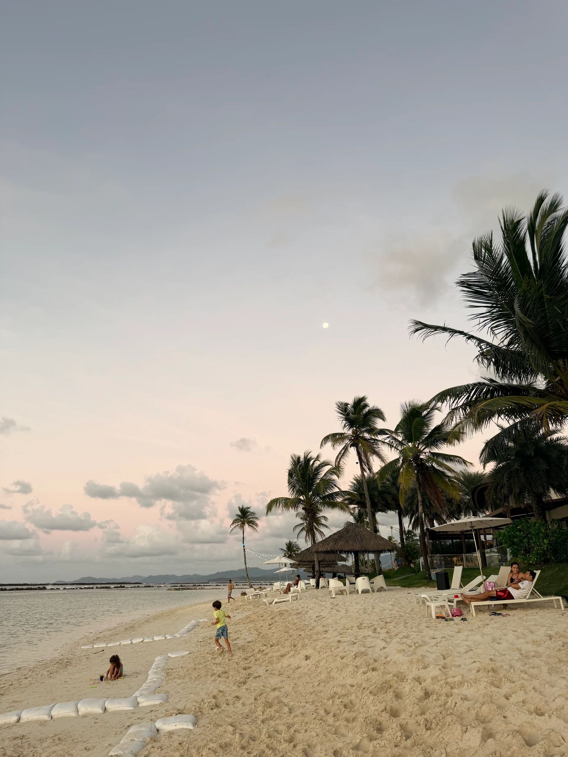 Tropical sunset at Kayuco Playa Escondida, Panama with palm trees and people on the beach.