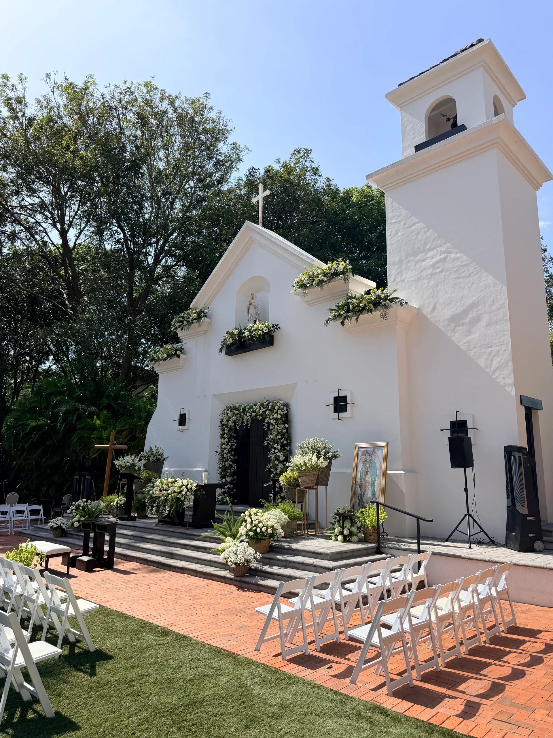 White chapel decorated with flowers for an outdoor wedding event