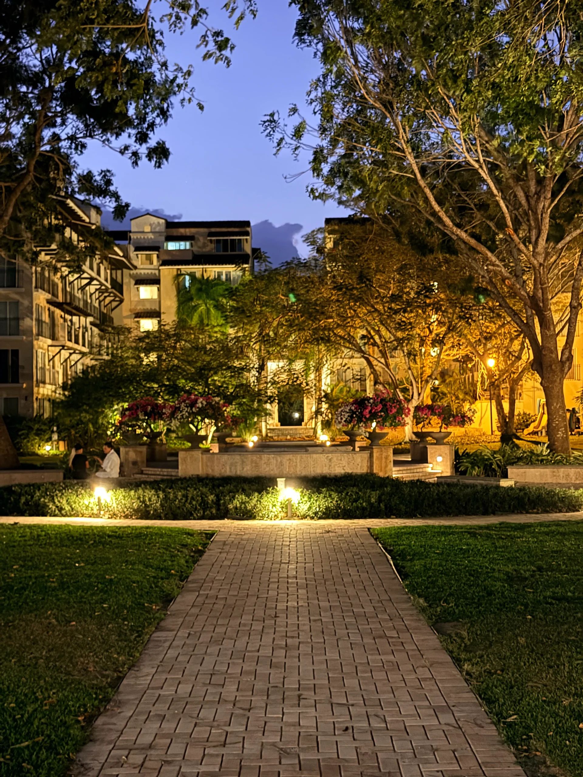 Paved walkway leading to a luxury hotel garden at dusk