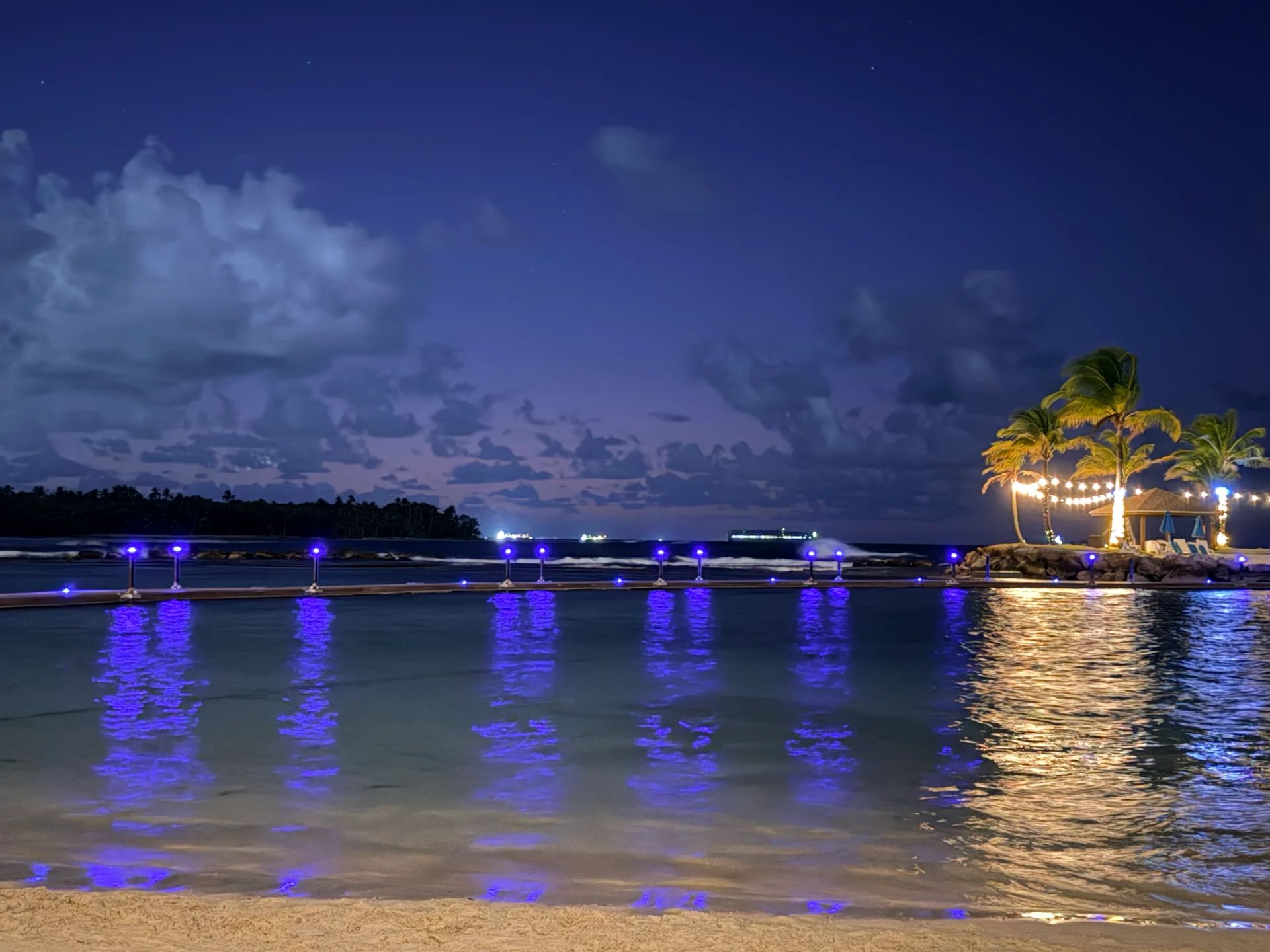 Luxury infinity pool with blue lights and palm trees at night in Playa Escondida, Panama